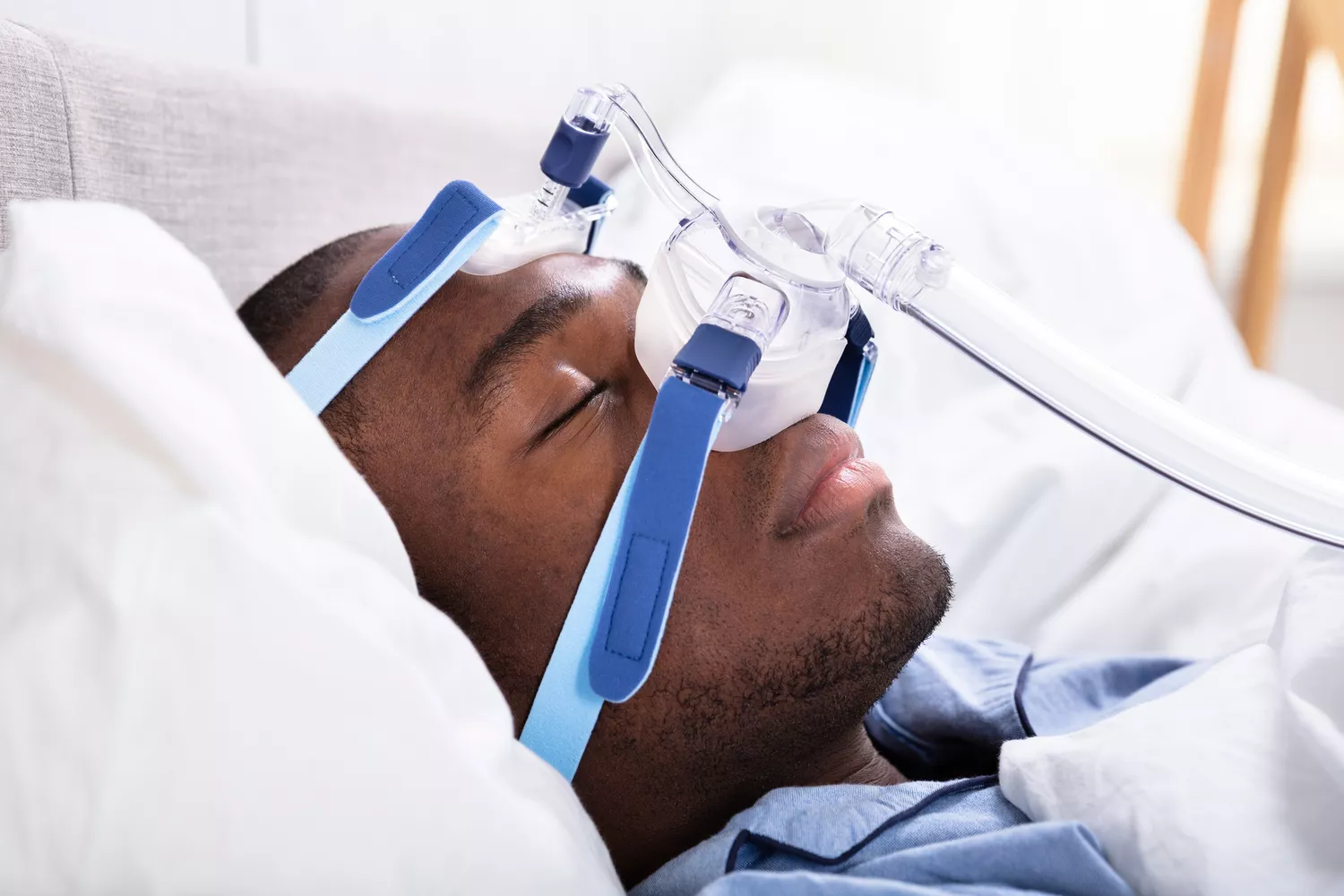 A young man sleeping soundly while wearing a CPAP mask used for treating sleep apnea.