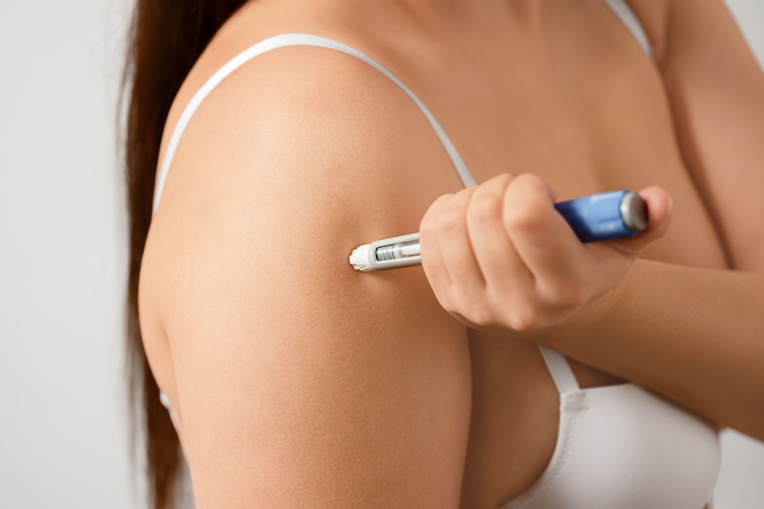 Close-up of a person using a medical injection pen on their upper arm for metabolic health management.