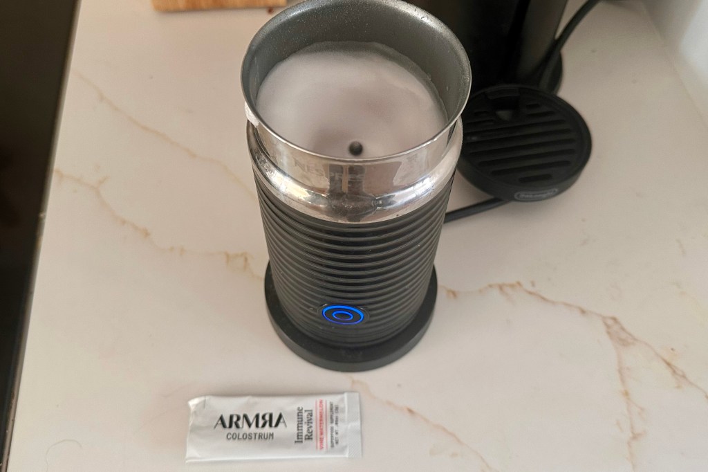 A person stirring ARMRA Colostrum powder into a glass of water.