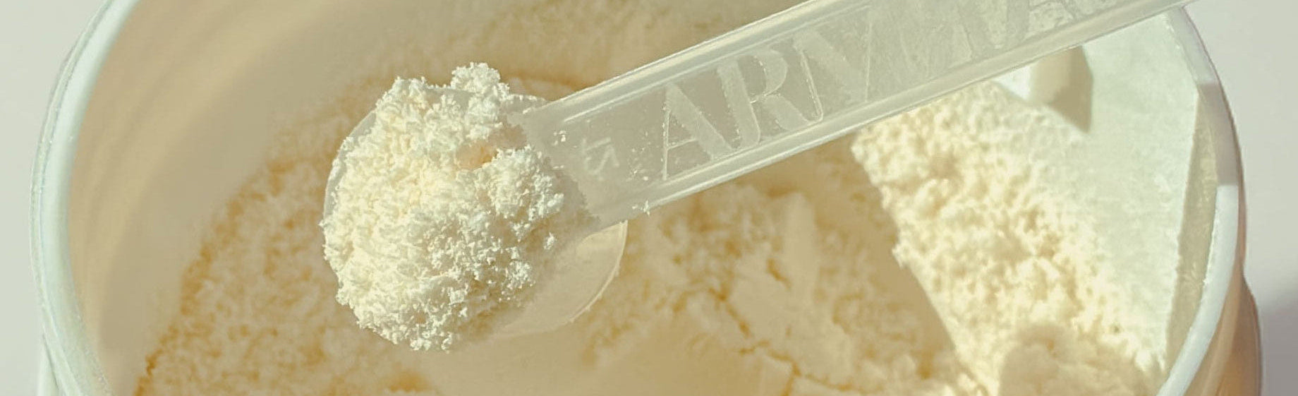 Close up of a scoop of ARMRA Colostrum in a glass jar.
