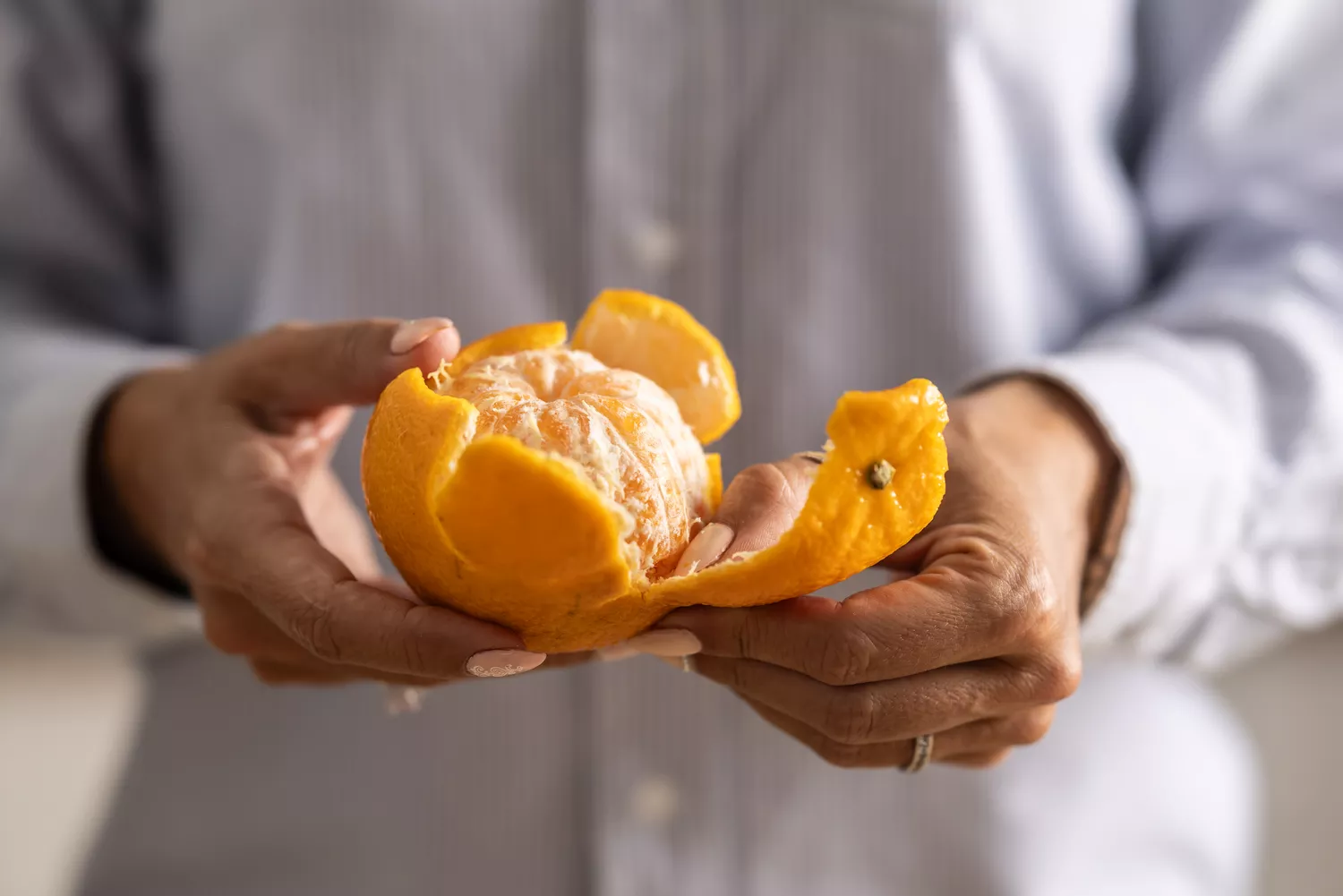 Person peeling a fresh orange, representing a focus on whole foods and vitamin intake.