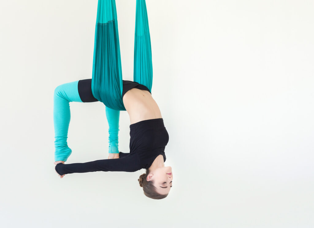An advanced practitioner performing an inverted bow pose using aerial fabric.