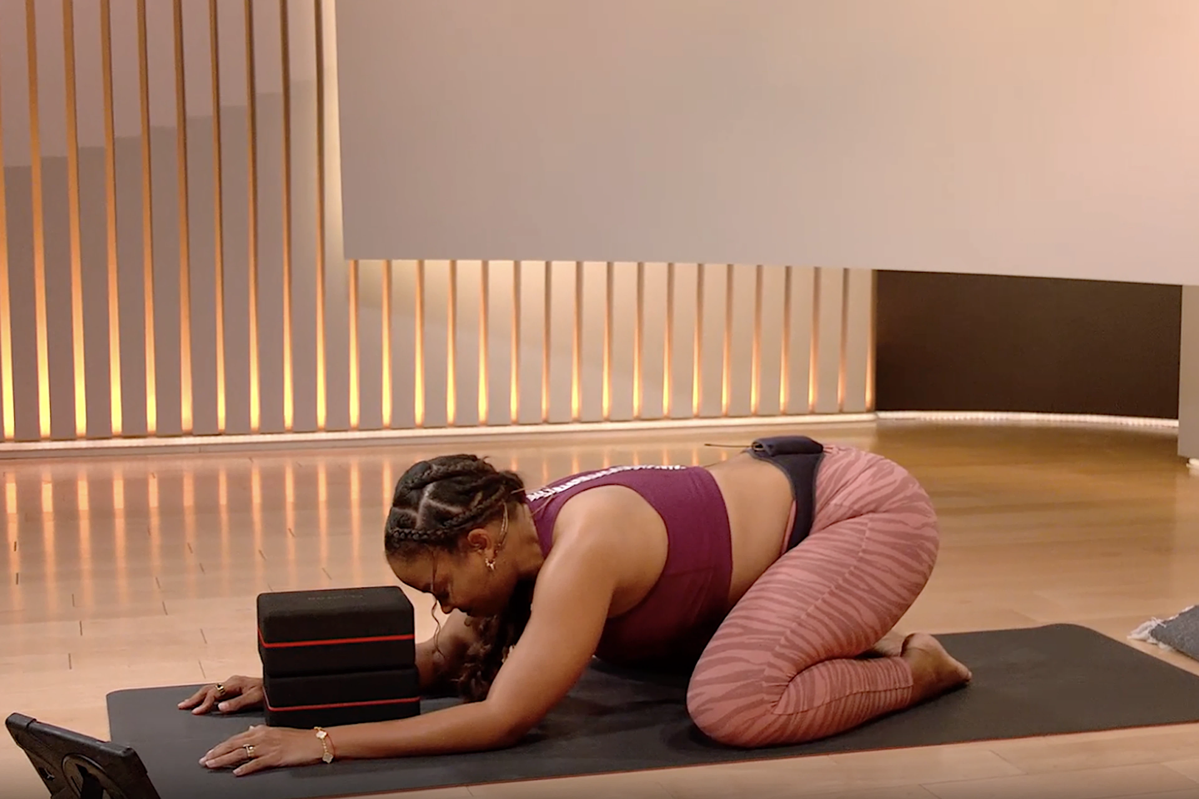 Yoga instructor Chelsea Jackson Roberts performing Child's Pose on a yoga mat.