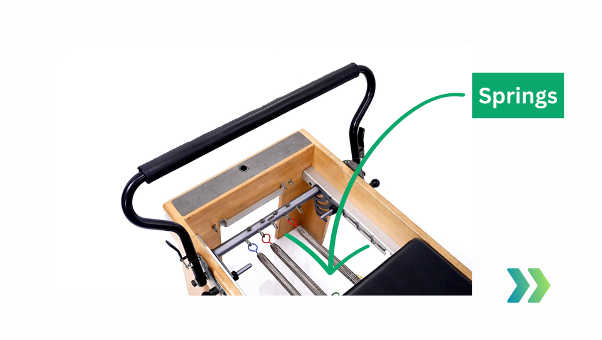 Close-up detail of the metal resistance springs on a Pilates reformer.