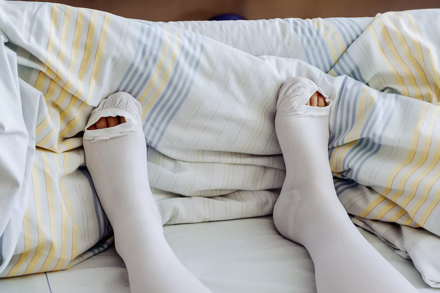 A person wearing beige-colored graduated compression stockings on their legs.