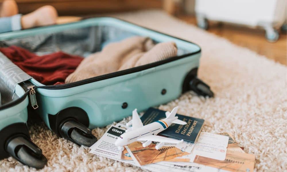 An open suitcase with a passport and a small airplane model, representing organized travel preparation.