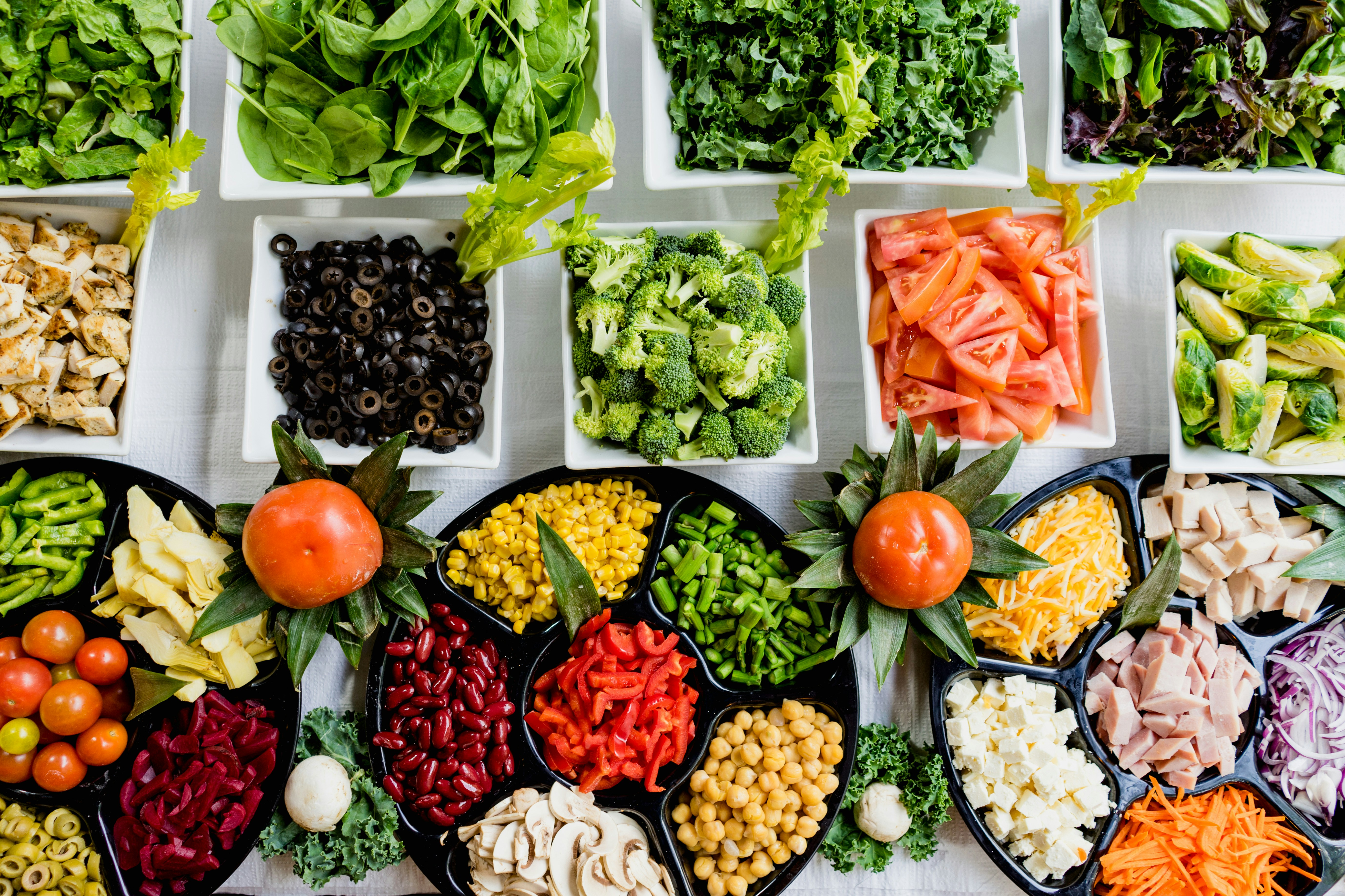 A person selecting fresh green vegetables at a grocery store produce section.