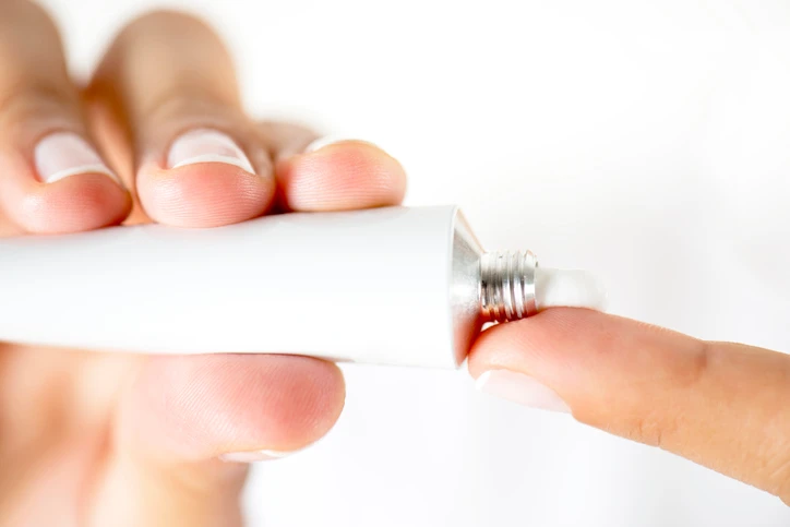 A small amount of white estradiol vaginal cream being held on a fingertip for application.