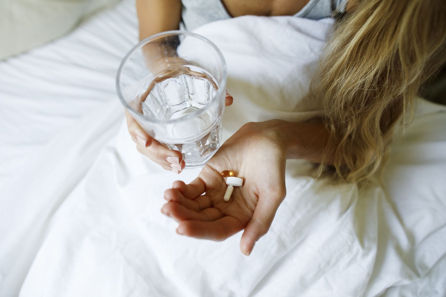A woman holding a glass of water and oral pills, representing the new pill-based administration options for semaglutide.